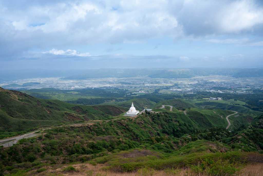 丘の上に建つ白い仏舎利塔と阿蘇谷の眺め